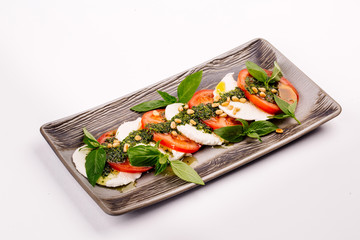 Tomato and mozzarella slices decorated with basil leaves on a plate
