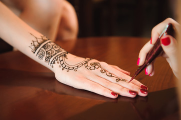 Master mehndi draws henna on a female hand.