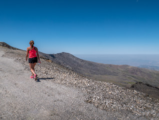 Fototapeta premium Young woman walking up to the top of the Sierra Nevada Mountain peak