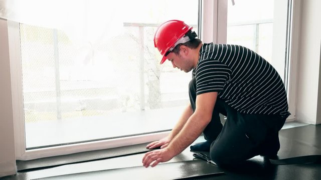 Male worker with scissors cutting teflon underlay mat