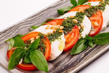 Tomato and mozzarella slices decorated with basil leaves on a plate