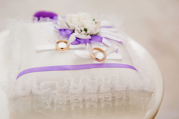 Obraz na płótnie Canvas Wedding rings on a cushion for rings in violet design
