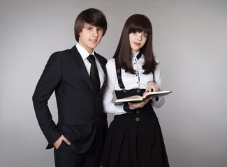 Happy teenagers in school uniform portrait. Handsome boy and beautiful brunette girl posing isolated on studio background.