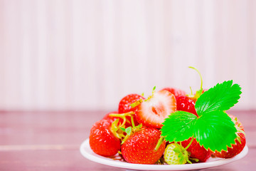 strawberries in bowl on wooden table with low key and copy space
