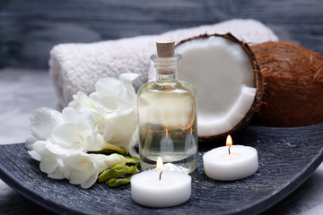 Plakat Composition with coconut oil in bottle for spa treatment on dark plate