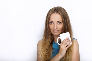 Headshot of young adorable playful blonde woman with cute smile in cobalt color blouse posing with big pure white mug on white backdrop