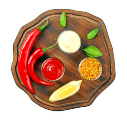 Wooden plate with different sauces, chili and lemon slice on white background