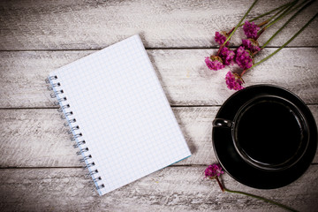 flowers on wooden table. copy space. workspace with notebook and coffee cup. celebration template concept.