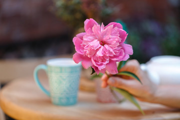 cups of tea and peony on wooden table in street cafe