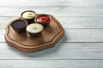Wooden plate with different sauces on table