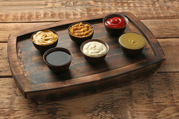 Wooden plate with different sauces on table