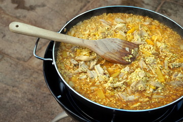 Pan of chicken paella cooking on an outdoor gas cooker
