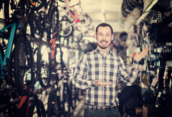 Fototapeta na wymiar admiring man in bicycle shop chooses for himself sports bike