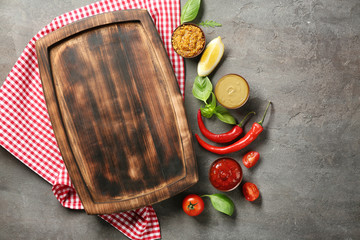 Wooden plate, different sauces and vegetables on gray background