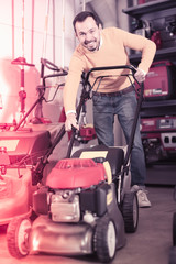 Fototapeta na wymiar friendly man deciding on best lawnmower in garden equipment shop