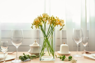 Beautiful composition with fresh freesia in vase on table