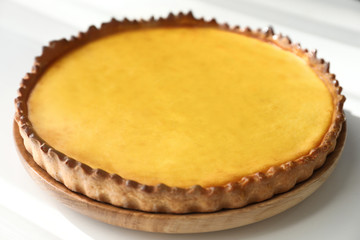 Wooden plate with tasty lemon curd pie on white table, closeup