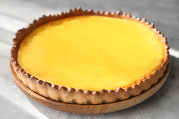 Wooden plate with tasty lemon curd pie on table, closeup