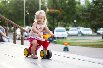 A little girl is riding a balance bike in the park.