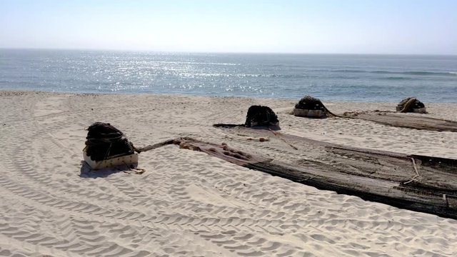 Arte Xavega fishing nets preparations arroung the typical portuguese old fishing boats on the beach in Paramos, Portugal.
