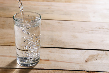 Pour drinking water into a glass of water.