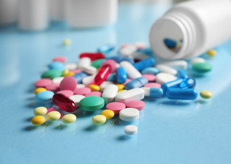 Plastic container and pills on color background
