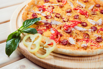 Pizza with salami on the wooden background