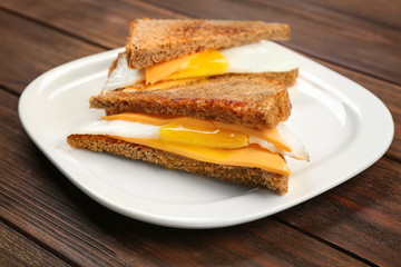 Delicious sandwiches with over easy egg and cheese on kitchen table