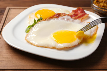 Eating delicious over easy eggs with bacon on kitchen table