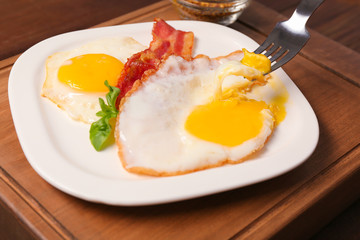 Eating delicious over easy eggs with bacon on kitchen table