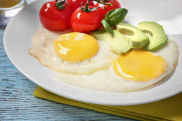 Delicious over easy eggs with avocado and tomatoes on kitchen table