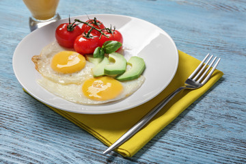 Delicious over easy eggs with avocado and tomatoes on kitchen table