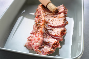 Baking tray with raw pork ribs and basting brush, closeup
