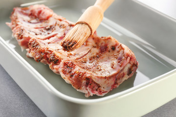 Baking tray with raw pork ribs and basting brush, closeup