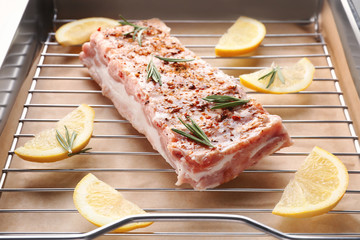 Baking tray with raw pork ribs and lemon slices, closeup