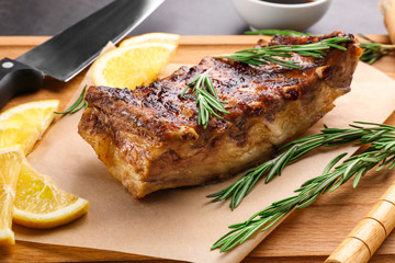 Wooden board with delicious pork ribs, closeup