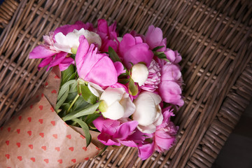 Beautiful bouquet with fragrant peonies on wicker surface