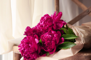 Bouquet of beautiful peonies on wooden chair