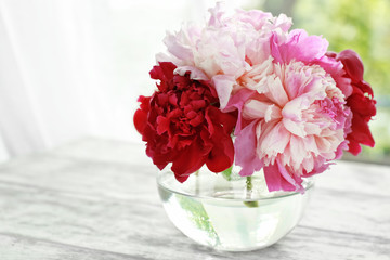 Vase with beautiful peony flowers on table