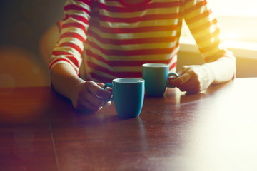 girl with two cups of coffee or tea in morning light offering one for us - 164636415