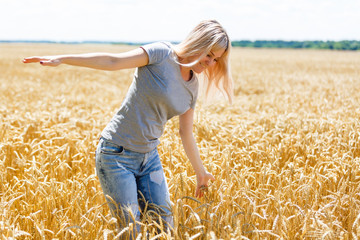 The girl put her hands in the wheat field