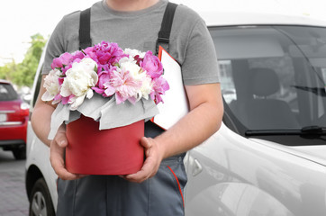 Delivery man with beautiful peony flowers in gift box outdoors