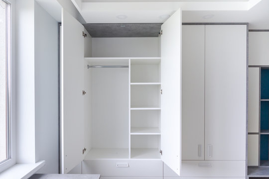 White empty closet for different clothes. A cupboard with shelves and hanger. 
