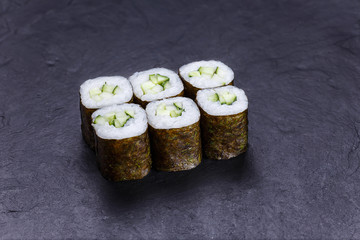 Sushi rolls with cucumber, served on black stone slate. Japanese food, vegetarian menu
