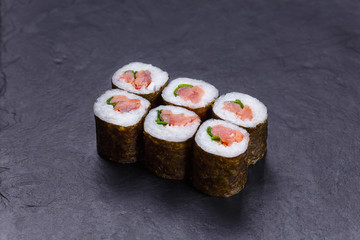 Traditional delicious Japanese food, sushi roll with salmon and scallion served on black slate.