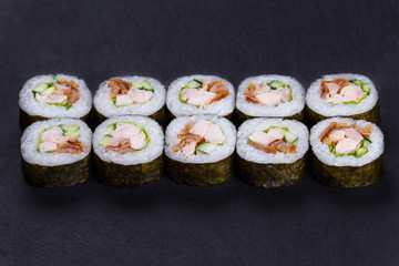 Futomaki sushi roll with redfish, omelet and cucumber served on black slate, delicious food