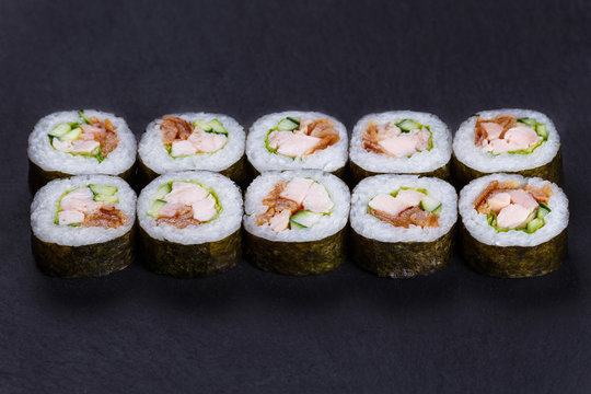 Futomaki sushi roll with redfish, omelet and cucumber served on black slate, delicious food