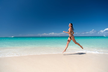 Fototapeta na wymiar Woman in swimsuit running on sea beach