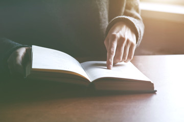 hands holding book and reading showing text with finger