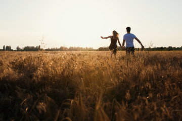 Romantic Couple at Sunset. Two people in love at sunset or sunrise. Man and woman on field
